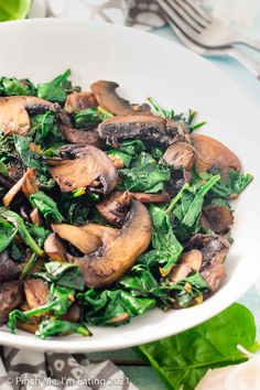 a white bowl filled with mushrooms and spinach on top of a blue table cloth