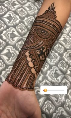 someone is showing off their henna tattoo on their arm and hand, which has an intricate design