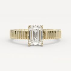 a yellow gold engagement ring with an emerald cut diamond in the center and thin band