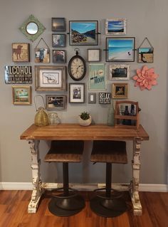 a table with two stools under a wall full of pictures and clocks on it