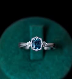 a blue diamond ring sitting on top of a green velvet