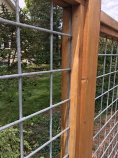 the side of a wooden fence with metal bars on it and grass in the background