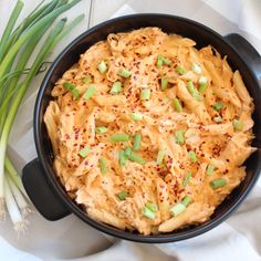 a black bowl filled with food on top of a white cloth next to green onions