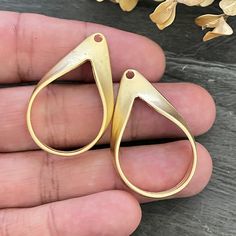 a pair of gold colored scissors are held in someone's hand next to flowers