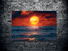 the sun is setting over the ocean with waves in front of an old brick wall