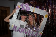 two people standing in front of a mirror holding up a sign with the number 28 on it