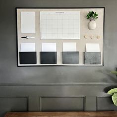 a wooden bench sitting in front of a gray wall with paint samples and a potted plant