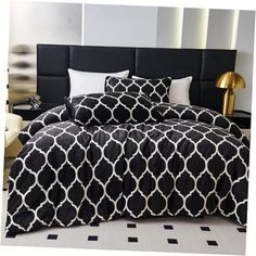 a bed with black and white comforters in a room next to a lamp on a table