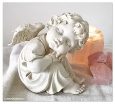 a statue of an angel sitting next to a piece of pink himalayan rock on a white blanket