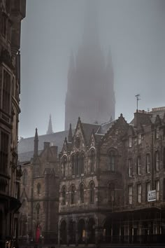 an old building with a clock tower in the background on a foggy, overcast day