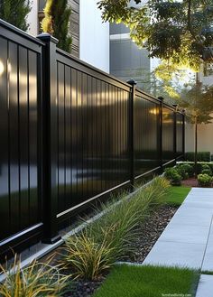 a long black fence next to a sidewalk