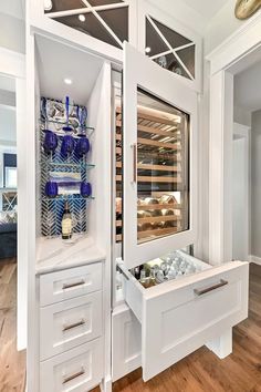 a wine cellar in the middle of a room with wooden floors and white cabinetry