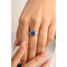 a woman's hand holding an engagement ring with a blue sapphire stone on it