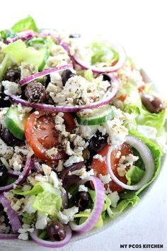 a salad with lettuce, tomatoes, olives and feta cheese on it