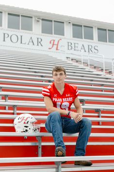 a young man sitting on top of a bleacher wearing a football jersey and jeans