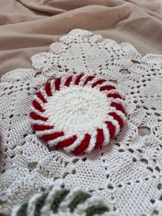 a red and white crochet doily with a candy cane on it sitting on top of a bed