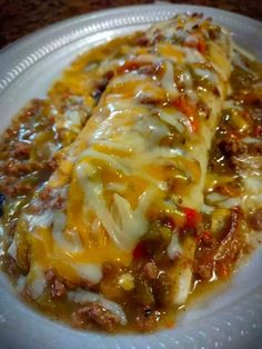 a white plate topped with meat and cheese covered enchilada casserole