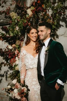 a bride and groom standing in front of a floral wall