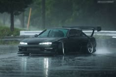 a black car driving down a rain soaked road