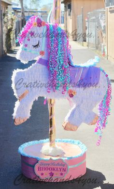 a pink and blue carousel horse on the street