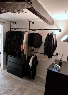 a room with clothes hanging on the wall and an alarm clock in front of it