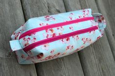 a blue and pink flowered bag sitting on top of a wooden fence