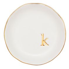 the letter k is inscribed on a white plate with gold trim and an initial in the middle