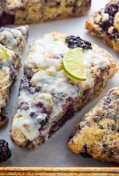 blueberry lime scones on a baking sheet with fresh blackberries and limes