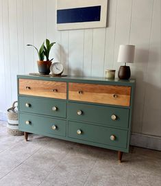 a green dresser with wooden drawers in a room