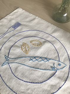 a white table cloth with an embroidered fish on it