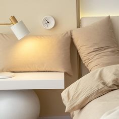 a bed with two pillows and a lamp on top of the night stand next to it