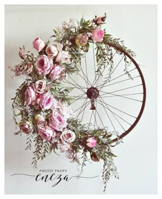 a bicycle wheel with pink flowers and greenery on the spokes is featured in this photo