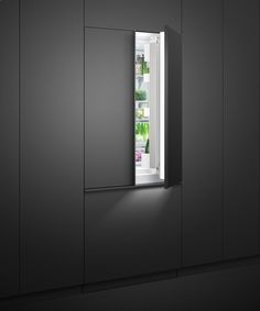 an open refrigerator door with the light on in a dark, dimly lit kitchen area