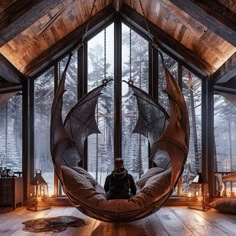 a man sitting in a hammock chair inside of a room filled with windows