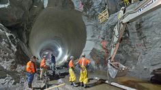 construction workers are standing in the middle of a tunnel