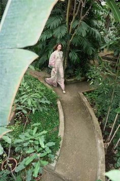 a woman is walking down a path in the jungle