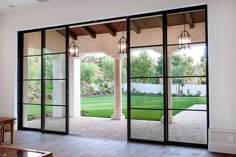 an empty room with large glass doors leading into the yard and lawn behind it,