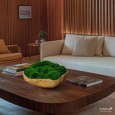 a wooden table topped with a bowl filled with broccoli next to a couch