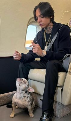 a man sitting on an airplane with his dog and looking at something in front of him