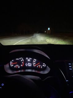 the dashboard of a car at night with its lights on and it's speedometer lit up