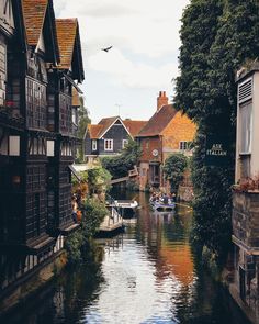 a river running through a small town next to tall buildings with windows on each side