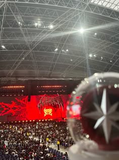 an audience at a concert is shown from the stage with red lighting and large screen