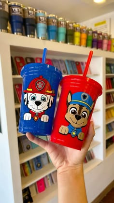 two children's cups with cartoon dogs on them in front of a store shelf