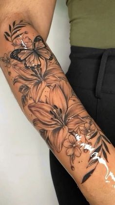 a woman's arm with flowers and butterflies tattooed on the side of her arm