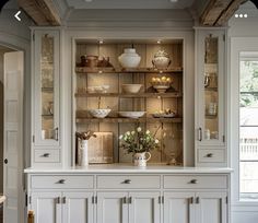 a kitchen with white cupboards and shelves filled with dishes on top of each other