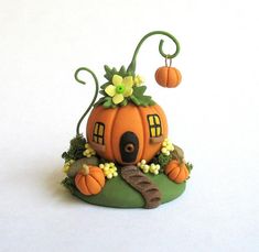 there is a small pumpkin house on top of a hill with flowers and leaves around it