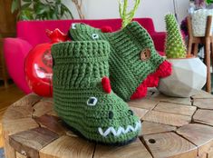 a pair of green knitted shoes sitting on top of a wooden table next to a potted plant