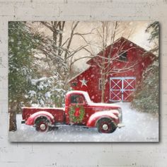 an old red truck parked in front of a barn with christmas decorations on the bed