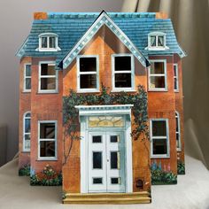 a doll house with an open front door and windows on the outside, painted to look like a brick building