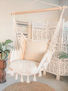 a white hanging chair next to a potted plant